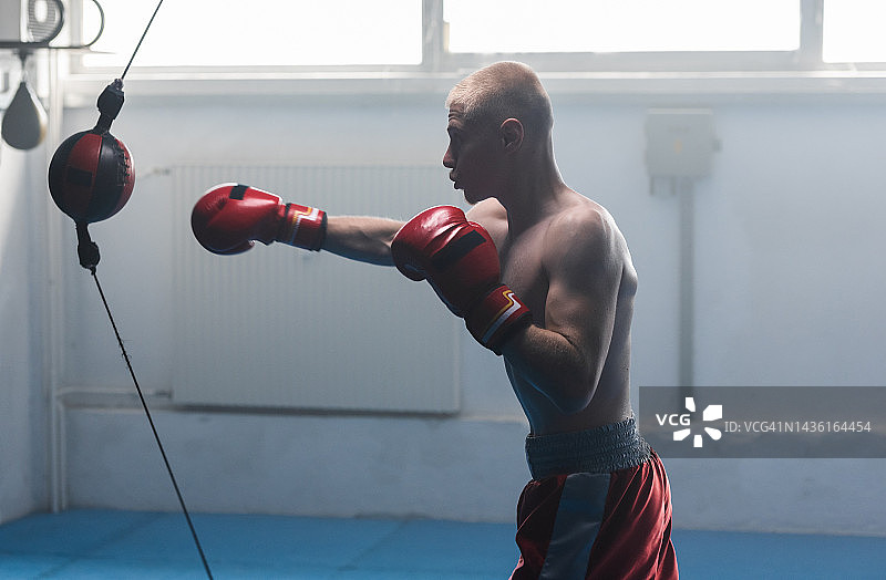 专注的年轻运动男子用拳击球练习拳击图片素材