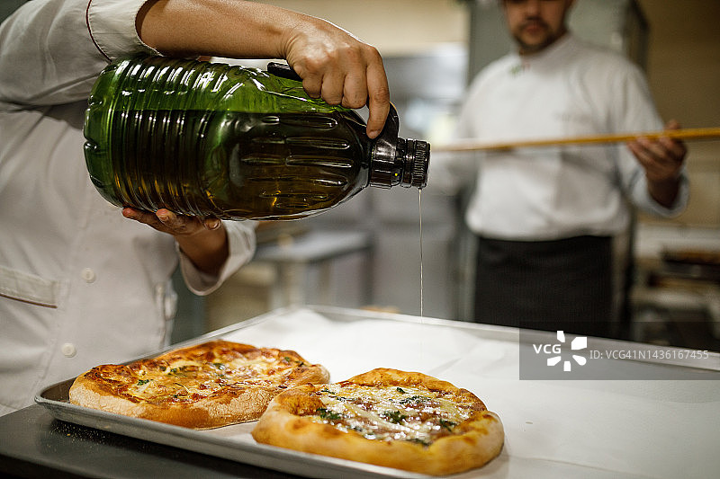 在披萨上涂抹橄榄油的人图片素材