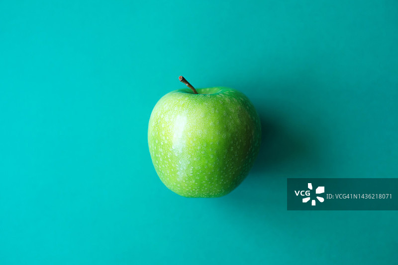 绿色背景上的绿苹果：单色水果背景，简约健康美食图片素材