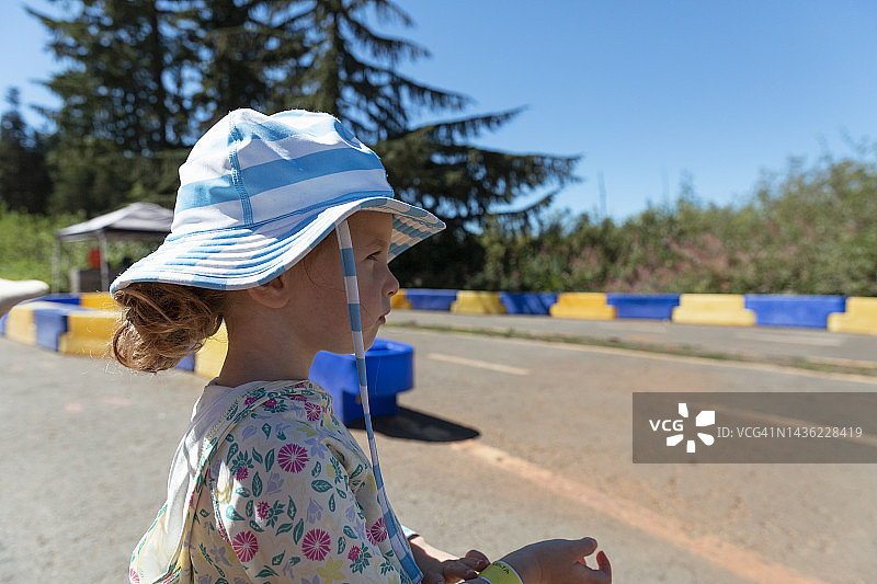 三岁女孩满怀期待地等待着在卡丁车赛道上行驶图片素材