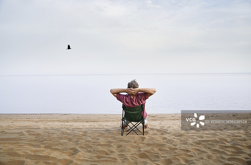 坐在沙滩折叠椅上放松的年长男人图片素材
