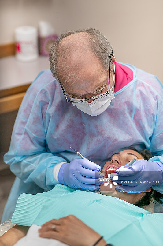 经验丰富的牙医为成年女性患者进行口腔护理图片素材