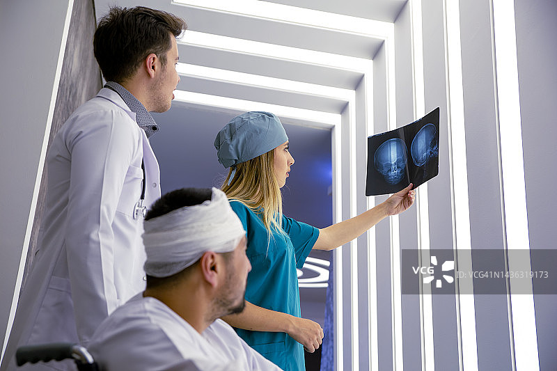 年轻医生正在查看病人头骨的X光片图片素材