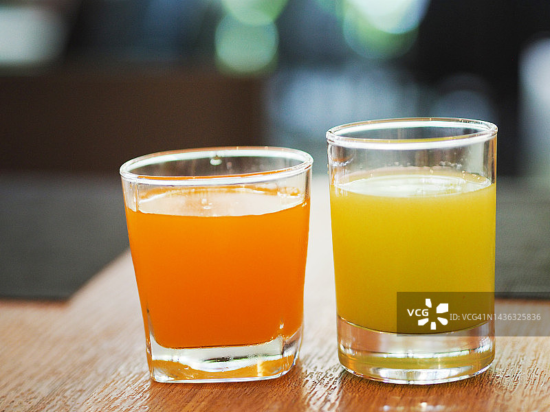 木桌上玻璃杯中的橙汁和番石榴汁图片素材
