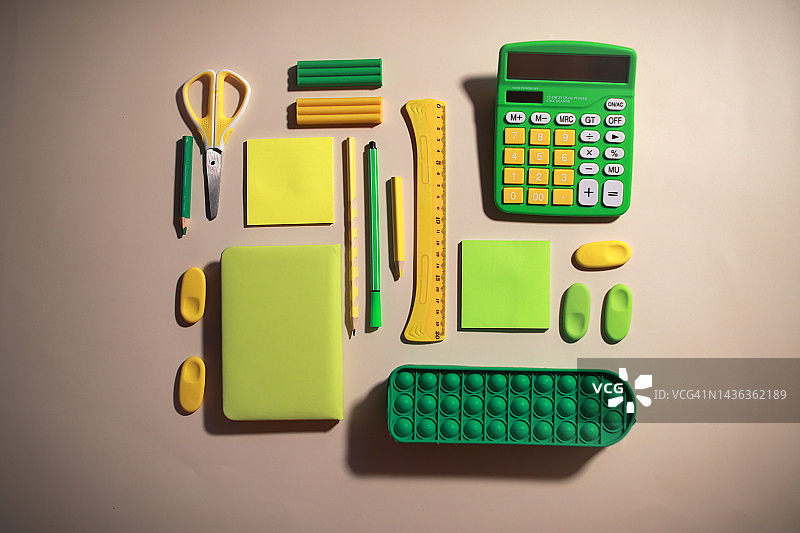 木桌上大量绿色和黄色学习或办公用品顶视图图片素材