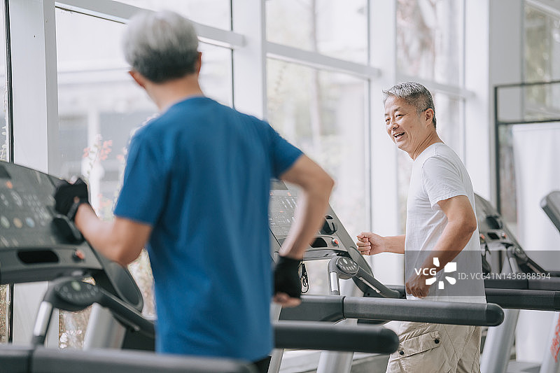 两名年长的中国男人在健身房一起跑步机上跑步图片素材