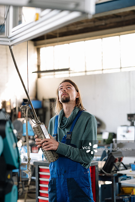 年轻男子在车间里用起重机工作图片素材