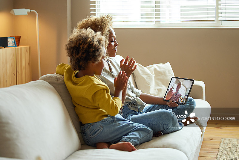 男孩和母亲向奶奶的平板电脑挥手图片素材