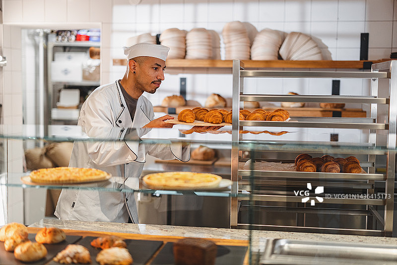 在厨房查看牛角包质量的专业面包师图片素材