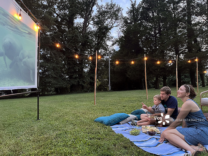 父母和小男孩在户外屏幕上看电影图片素材