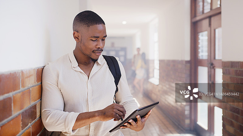 男大学生在教学楼走廊使用平板电脑学习图片素材