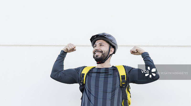 戴自行车头盔的快递员展示肱二头肌图片素材