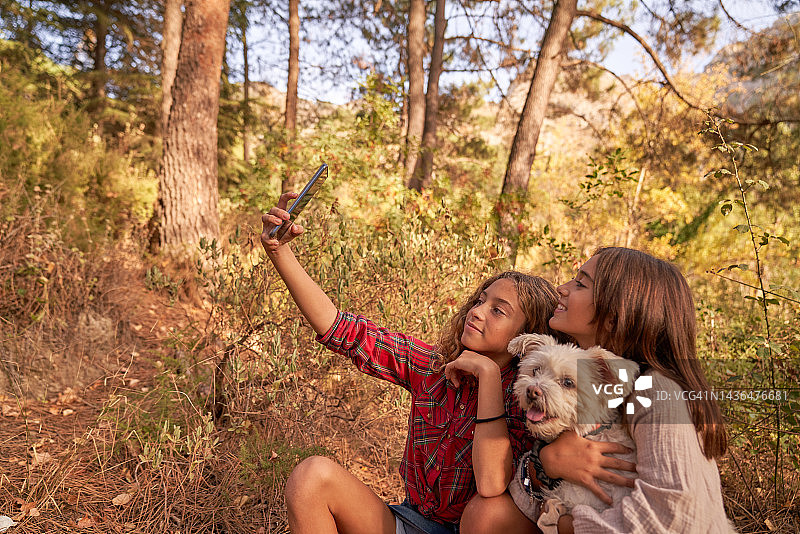 两个女孩和她们的狗在森林里自拍图片素材
