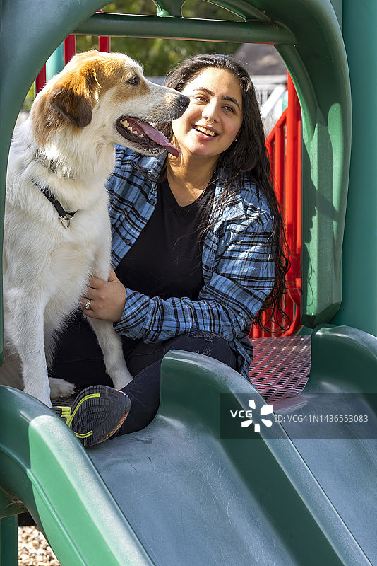 印度年轻人在当地的宠物公园和游乐场和她的狗一起玩耍图片素材