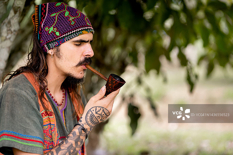 坐在外面抽烟斗的嬉皮士男人图片素材