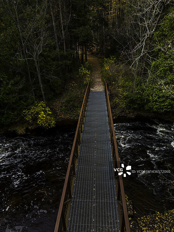 森林中横跨河流的钢桥徒步道图片素材