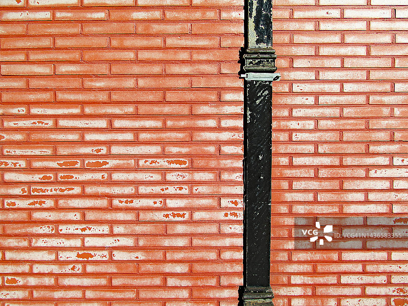 比利时布鲁塞尔砖墙上风化剥落的白色油漆和黑色金属管图片素材