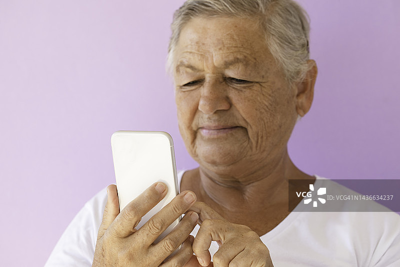 年长的女人在使用智能手机图片素材
