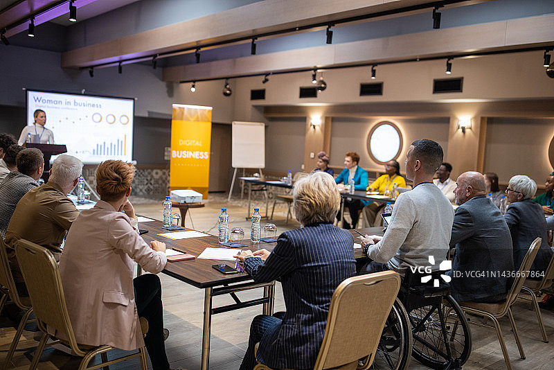 商务会议：与会者聆听年轻女性的演讲图片素材