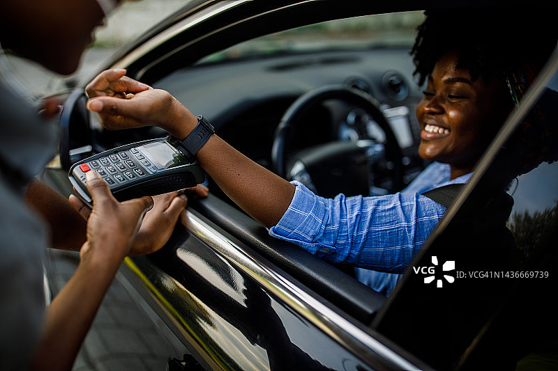 年轻女子在路边取货时使用智能手表支付图片素材