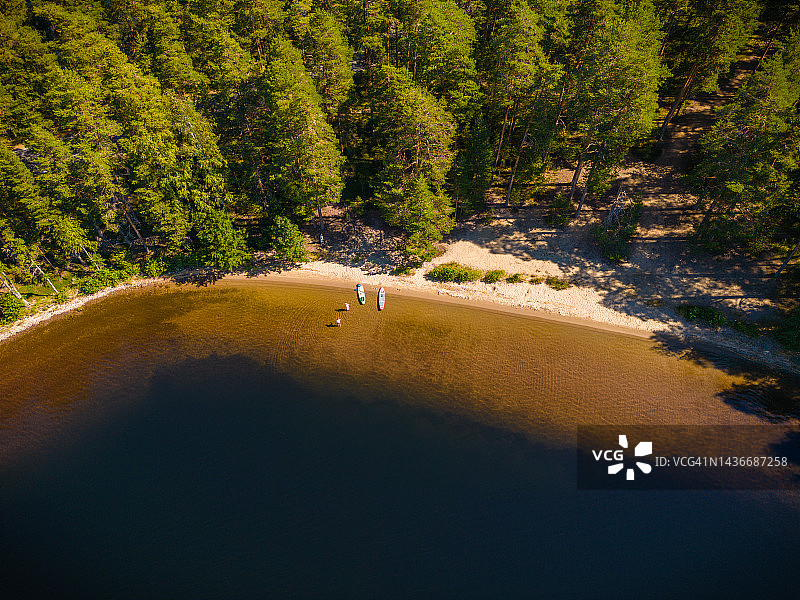在芬兰蓬卡哈尤一个偏远沙滩上，两个桨板运动员在阳光明媚的夏日里划桨的航拍图片素材