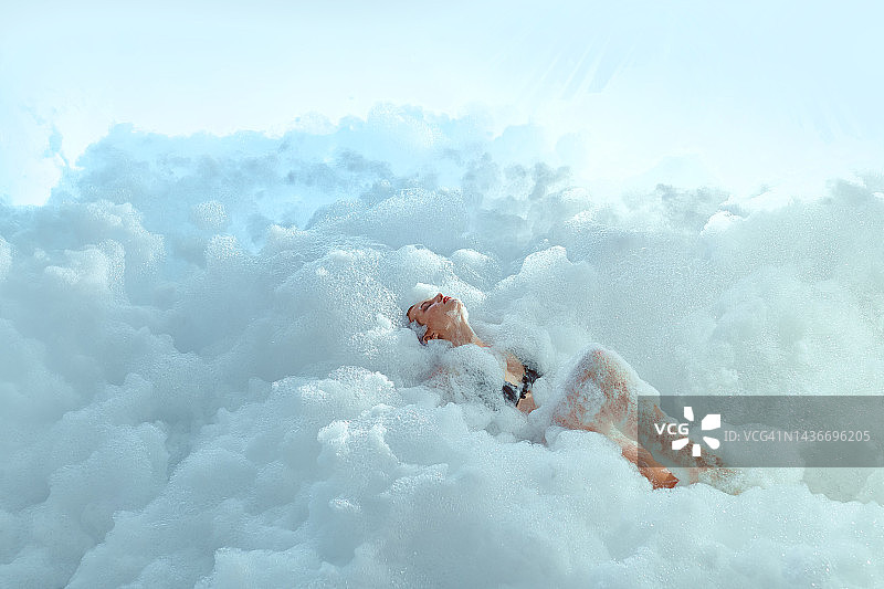 在泡泡云上放松的红发蓝眼漂亮女人，自我护理和健康隐喻图片素材