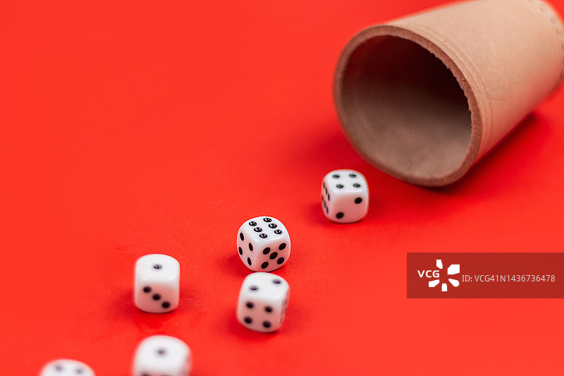 红色背景上从骰盅中洒出的骰子图片素材