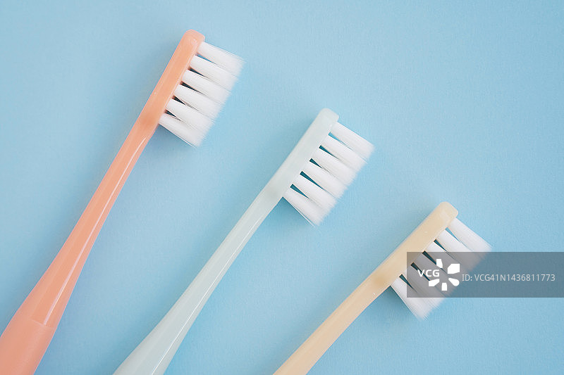 蓝色背景上的三把彩色软毛牙刷图片素材