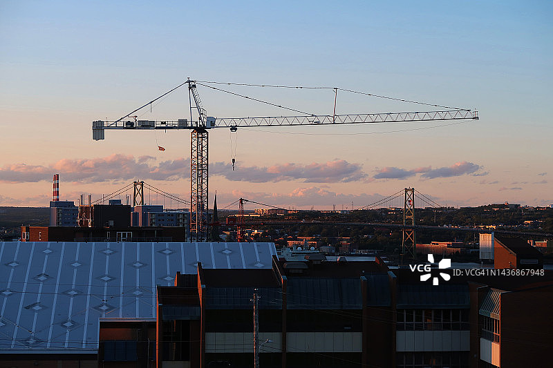 夕阳下桥梁和城市景观中的建筑起重机图片素材