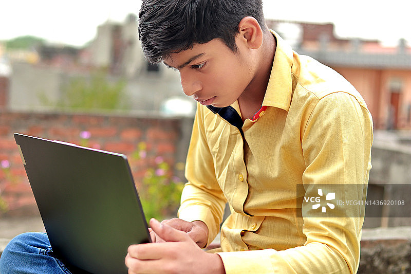 使用笔记本电脑的印度青少年男孩图片素材