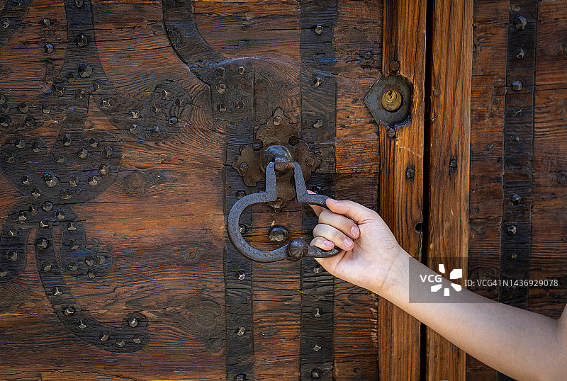 孩子的手拿着一个心形门把手，由古董木制成图片素材