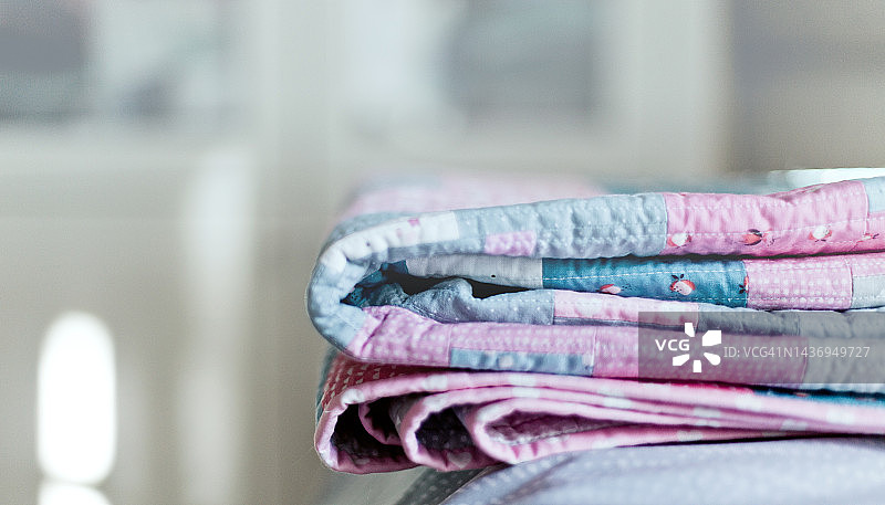 卷起的床罩，粉彩色拼接毯，斯堪的纳维亚风格灰色、粉色和蓝色条纹被子图片素材