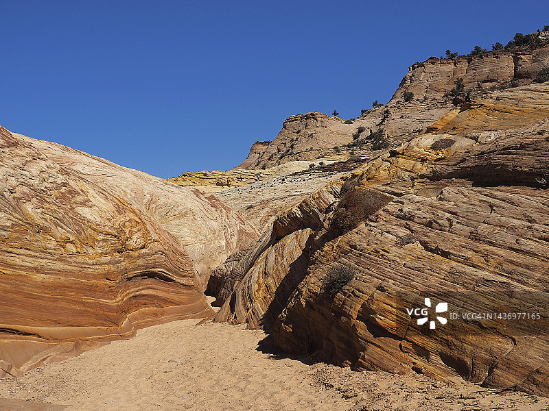 穿越犹他州大阶梯埃斯卡兰特国家纪念碑大角峡谷的沙质徒步小径图片素材