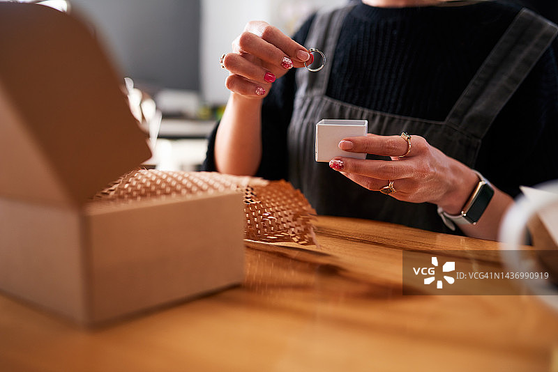 时尚：珠宝店和工人拿着戒指，为初创电子商务业务。珠宝设计师将订婚戒指放入盒子中，为设计工作室或工作室的客户准备，时尚行业的礼品包装图片素材