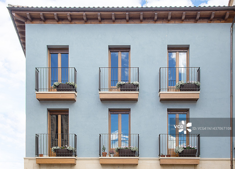 蓝色外墙与阳台，映衬着多云的天空图片素材