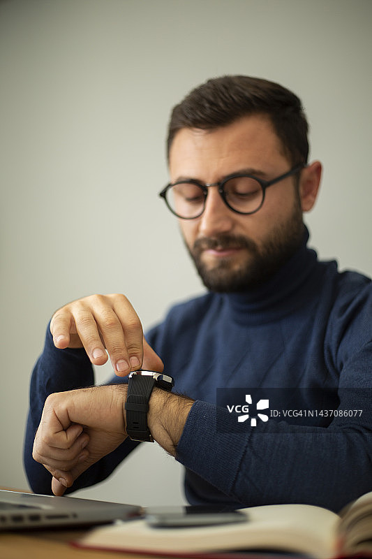 等待会议的年轻男商人，手持时钟图片素材