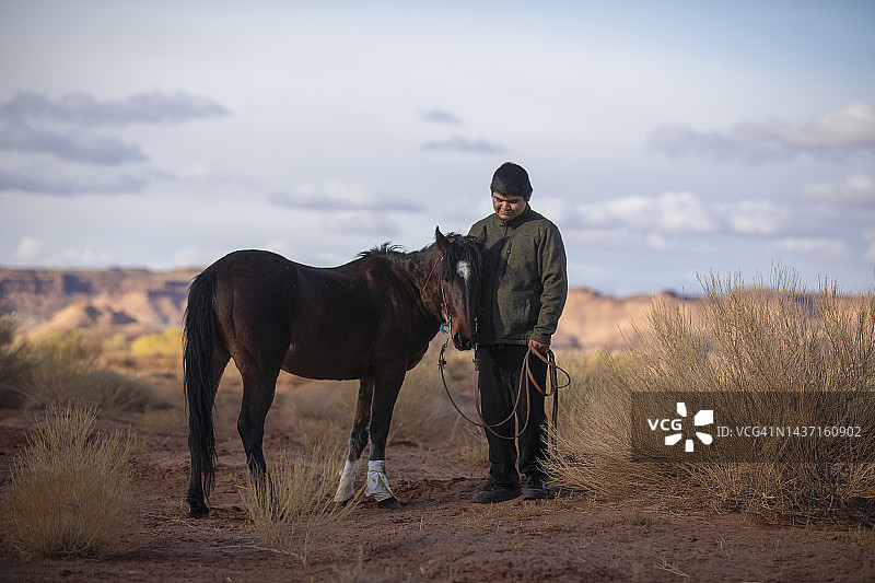 在纪念碑谷的纳瓦霍族少年和他的马图片素材