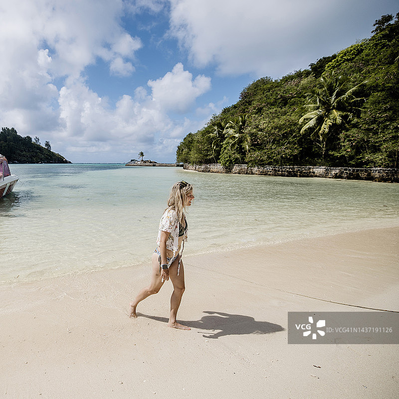 女人从船上走向沙滩岸边图片素材