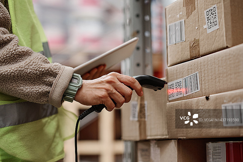 物流专员在仓库扫描纸箱上的二维码图片素材