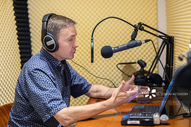 年长的男人戴着耳机在隔音录音棚里录制播客图片素材