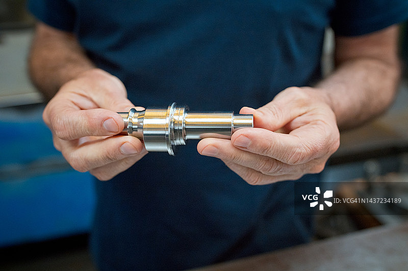 男工程师在工业中手持机器零件的身体中部图片素材