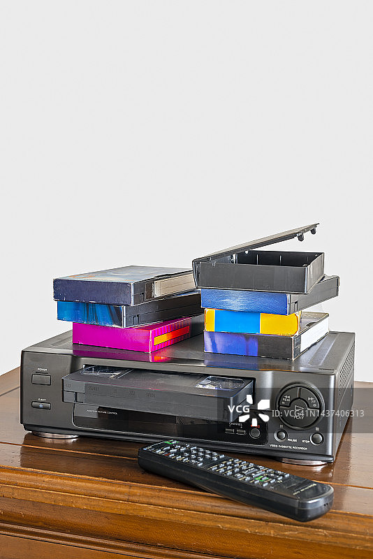 木柜上的旧录像机、遥控器和录像带图片素材