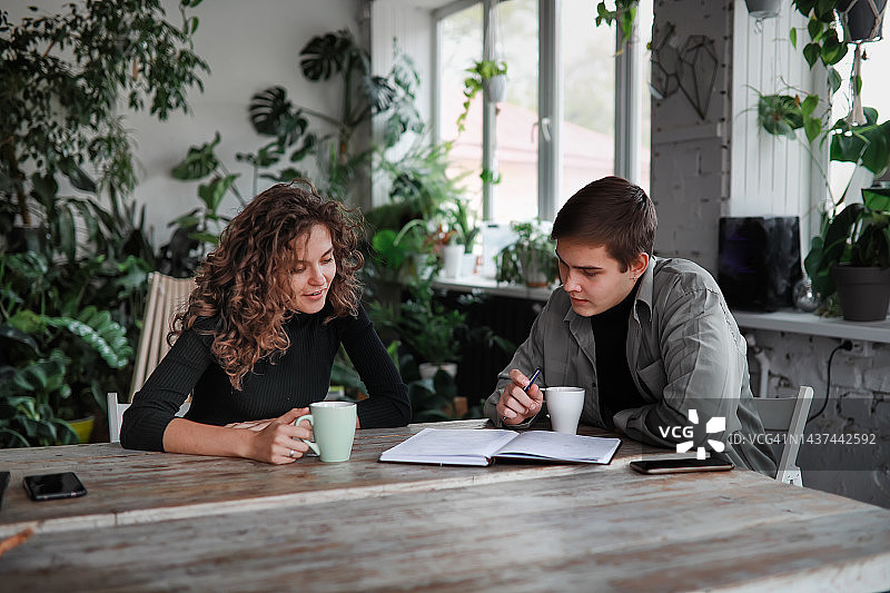 同事们在办公室外一起讨论项目。年轻男女在环保绿色办公室工作。图片素材