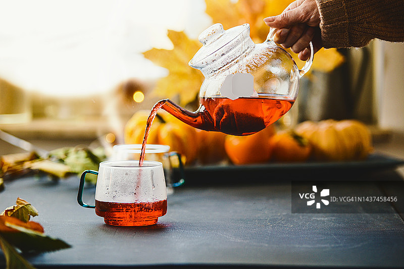 秋季，女人手在窗边桌上倒茶图片素材