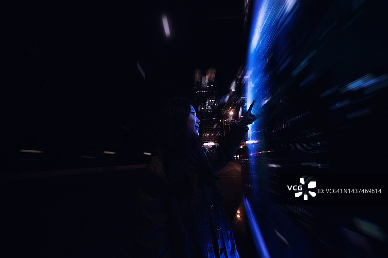 年轻的亚洲女性在金融区使用触摸屏图片素材