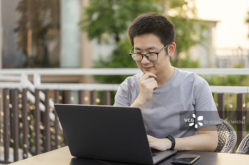 在露天咖啡馆使用笔记本电脑的亚洲自由职业者图片素材