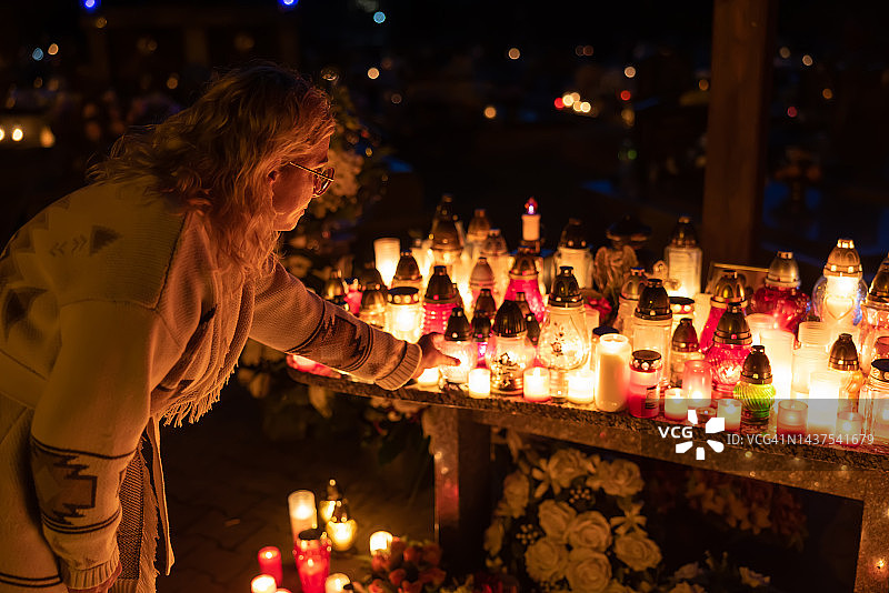 女人在墓地点燃蜡烛，缅怀逝者图片素材