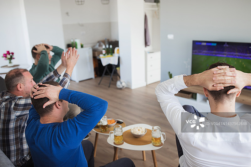紧张的男人们观看电视足球比赛的背影图片素材