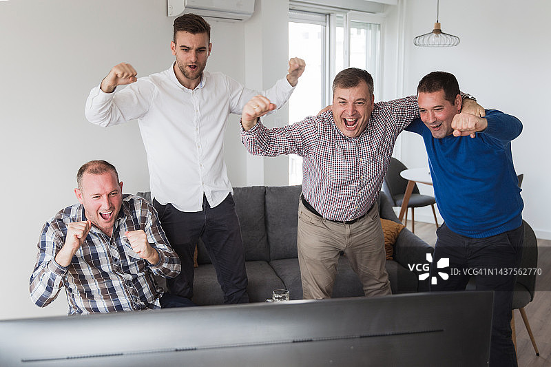 足球爱好者在电视上看足球比赛时拥抱庆祝图片素材