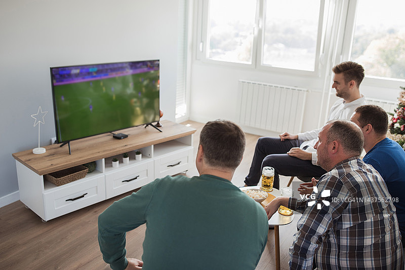 男人们坐在家里观看体育锦标赛图片素材
